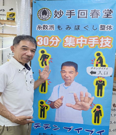 チチンプイプイの店舗案内の横断幕を紹介する店主
