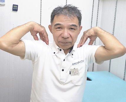椅子に座って肩まわりのセルフケアを実演するチチンプイプイ店主